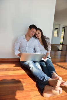 happy young relaxed  couple working on laptop computer at modern home indoor