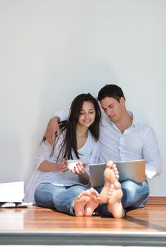 happy young relaxed  couple working on laptop computer at modern home indoor