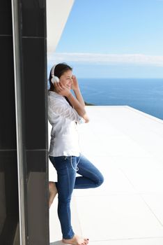 Young relaxed girl listening to the music on white headphones  in modern home interior