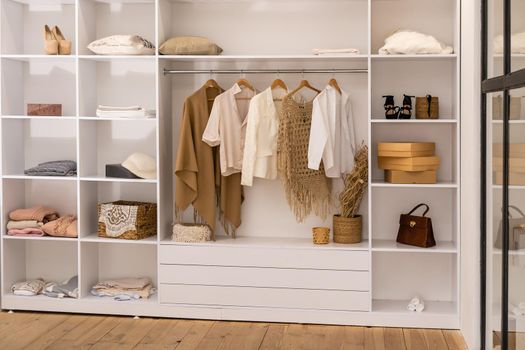 clothes hanging on rail in white wardrobe with boxes.