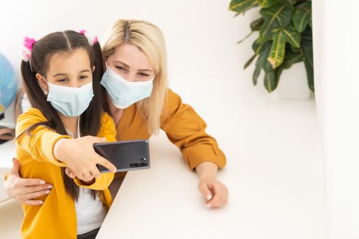 Little girl and her young mother taking a selfie wearing surgical mask