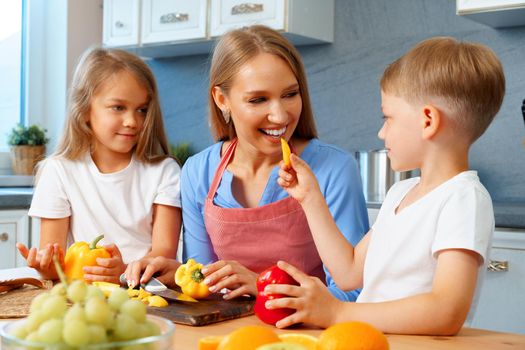 Young mother cooking with her children in kitchen