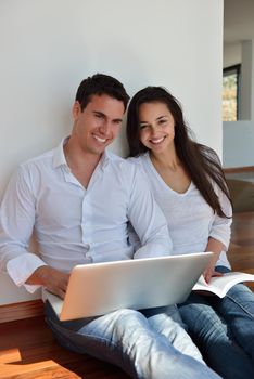 happy young relaxed  couple working on laptop computer at modern home indoor