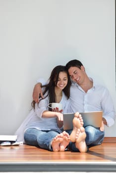 happy young relaxed  couple working on laptop computer at modern home indoor