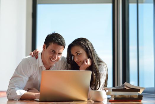 happy young relaxed  couple working on laptop computer at modern home indoor