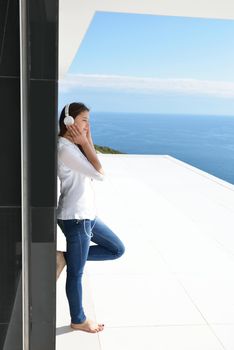 Young relaxed girl listening to the music on white headphones  in modern home interior