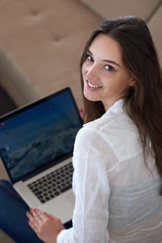 beautiful young woman relax and work on laptop computer modern  home office while listening musin on white headphones