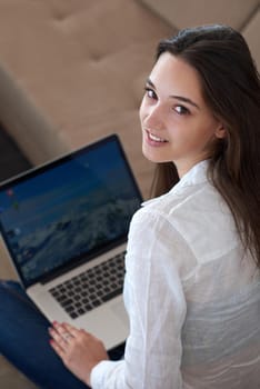 beautiful young woman relax and work on laptop computer modern  home office while listening musin on white headphones