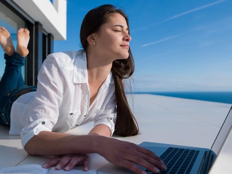 beautiful young woman relax and work on laptop computer  and read book at modern  home