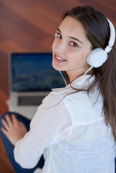 beautiful young woman relax and work on laptop computer modern  home office while listening musin on white headphones