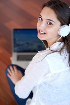 beautiful young woman relax and work on laptop computer modern  home office while listening musin on white headphones