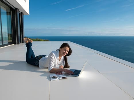 beautiful young woman relax and work on laptop computer  and read book at modern  home