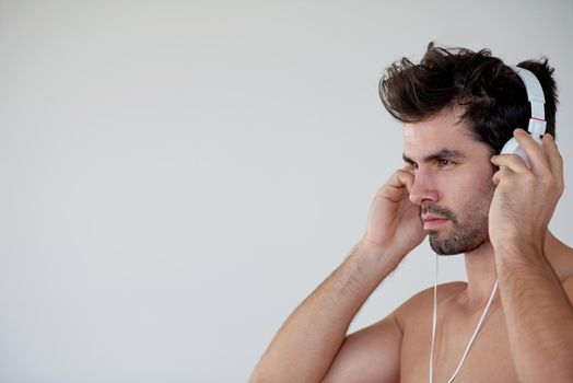 handsome young man listening music on headphones at modern home over  white wall and standing on hands