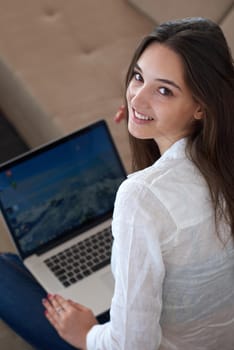 beautiful young woman relax and work on laptop computer modern  home office while listening musin on white headphones