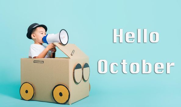 Hello October, Happy Asian children boy smile in driving play car creative by a cardboard box imagination with megaphone, studio shot on blue background