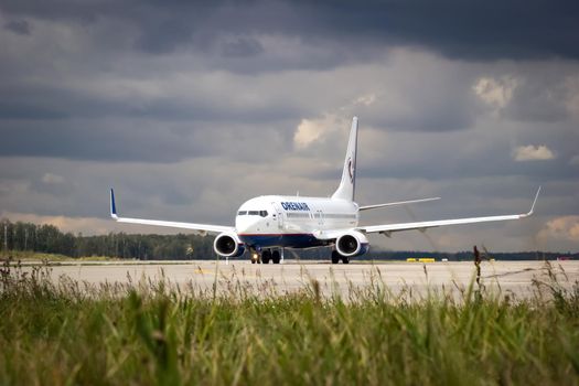 Russia, Moscow, Domodedovo Airport - September 09, 2015: A white passenger plane aircompany Orenair, is standing on runway against the background of storm clouds. Close up