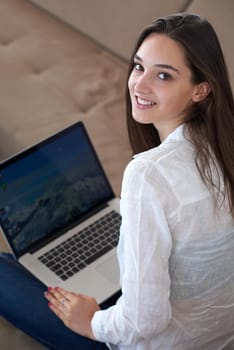 beautiful young woman relax and work on laptop computer modern  home office while listening musin on white headphones