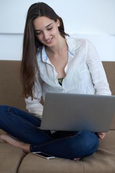 beautiful young woman relax and work on laptop computer modern  home office while listening musin on white headphones