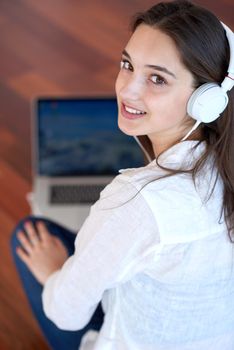 beautiful young woman relax and work on laptop computer modern  home office while listening musin on white headphones