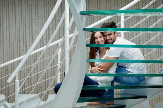 relaxed young couple on spiral glass stairs in modern home villa indoors