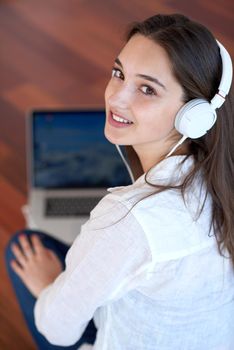 beautiful young woman relax and work on laptop computer modern  home office while listening musin on white headphones