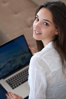 beautiful young woman relax and work on laptop computer modern  home office while listening musin on white headphones