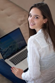 beautiful young woman relax and work on laptop computer modern  home office while listening musin on white headphones