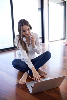 beautiful young woman relax and work on laptop computer modern  home office while listening musin on white headphones