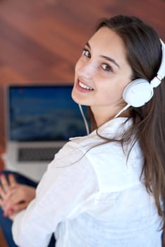 beautiful young woman relax and work on laptop computer modern  home office while listening musin on white headphones