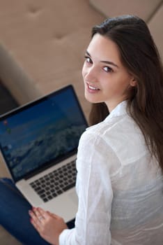 beautiful young woman relax and work on laptop computer modern  home office while listening musin on white headphones