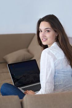 beautiful young woman relax and work on laptop computer modern  home office while listening musin on white headphones