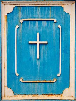 Old metal cross on blue door christian symbol