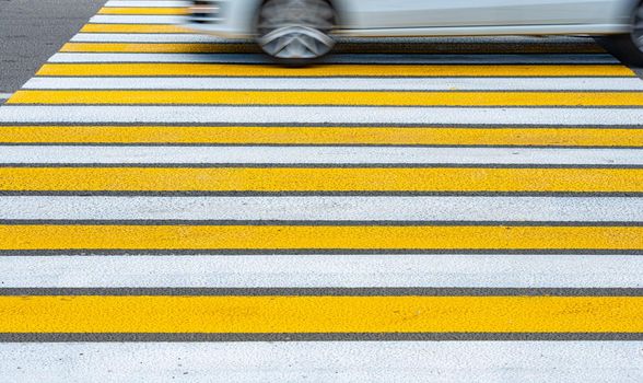 Yellow and white pedestrian crossing and car