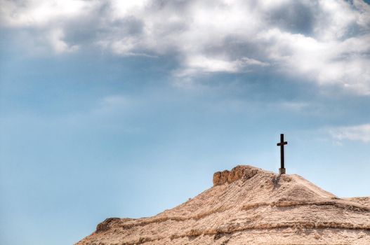 cross on the mountain with blue cloudy sky in background