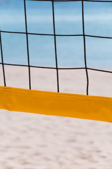 yellow volleyball net on the sand beach with blue sea in background