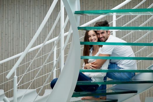 relaxed young couple on spiral glass stairs in modern home villa indoors