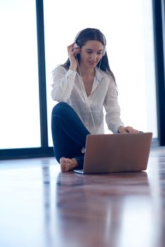 beautiful young woman relax and work on laptop computer modern  home office while listening musin on white headphones