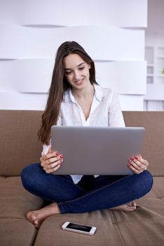 beautiful young woman relax and work on laptop computer modern  home office while listening musin on white headphones