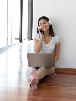 beautiful young woman relax and work on laptop computer modern  home office while listening musin on white headphones