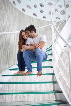 relaxed young couple on spiral glass stairs in modern home villa indoors