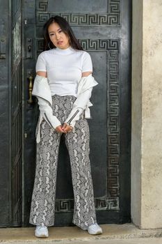 A beautiful cheeky young woman in front of an old huge door.