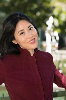 BBeautiful and happy mid age Chinise woman in a park on a sunny day.