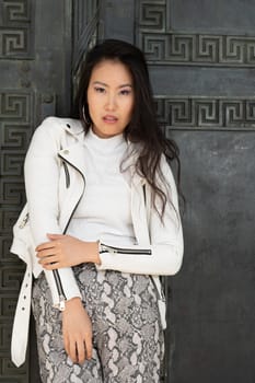 A beautiful cheeky young woman in front of an old huge door.