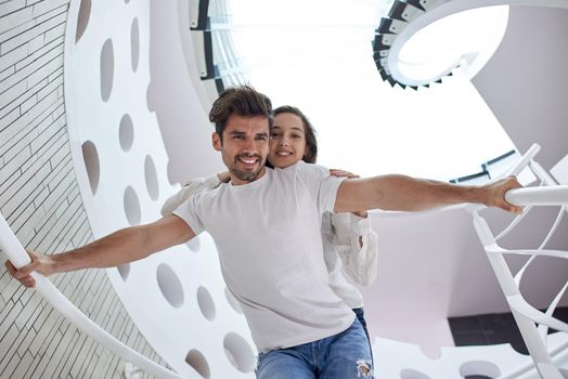 relaxed young couple on spiral glass stairs in modern home villa indoors