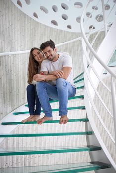 relaxed young couple on spiral glass stairs in modern home villa indoors