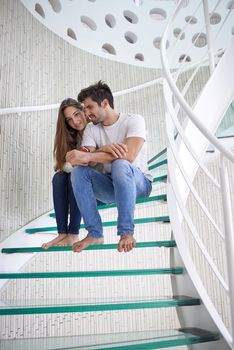 relaxed young couple on spiral glass stairs in modern home villa indoors