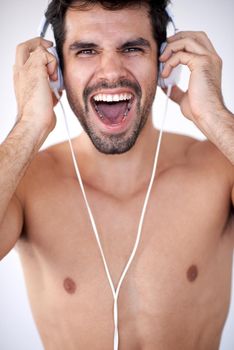 handsome young man listening music on headphones at modern home over  white wall and standing on hands