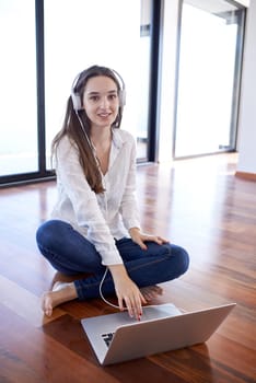 beautiful young woman relax and work on laptop computer modern  home office while listening musin on white headphones