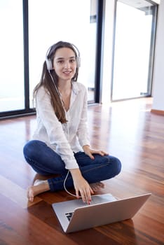 beautiful young woman relax and work on laptop computer modern  home office while listening musin on white headphones