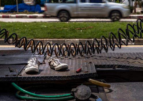 An old pair of dirty white sneakers shoe left on behind a truck. Symbolic way : the abandoned, No focus, specifically.